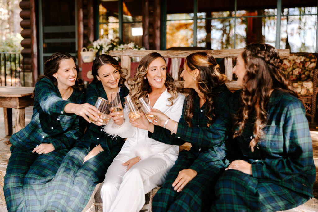 Bride cheers with bridesmaids before wedding day on Sebago lake
