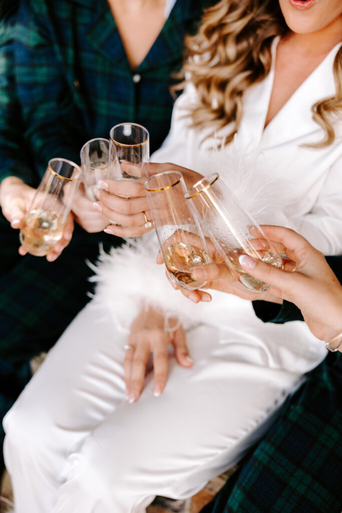 Bride cheers with bridesmaids before wedding day on Sebago lake