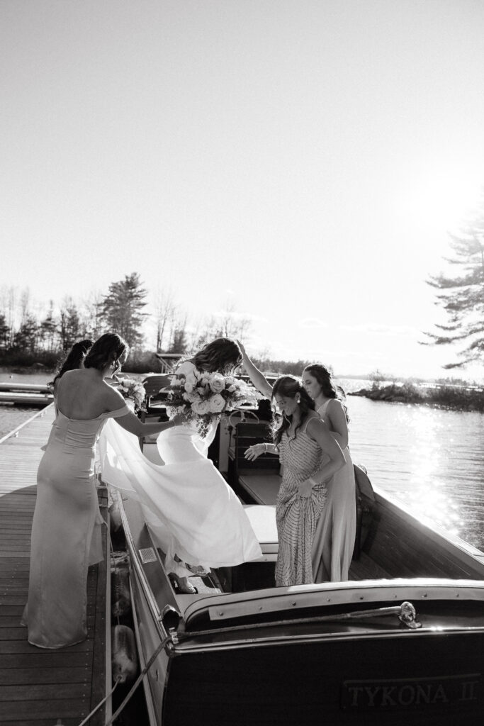 Bride gets on boat to head to ceremony on Sebago lake in Maine