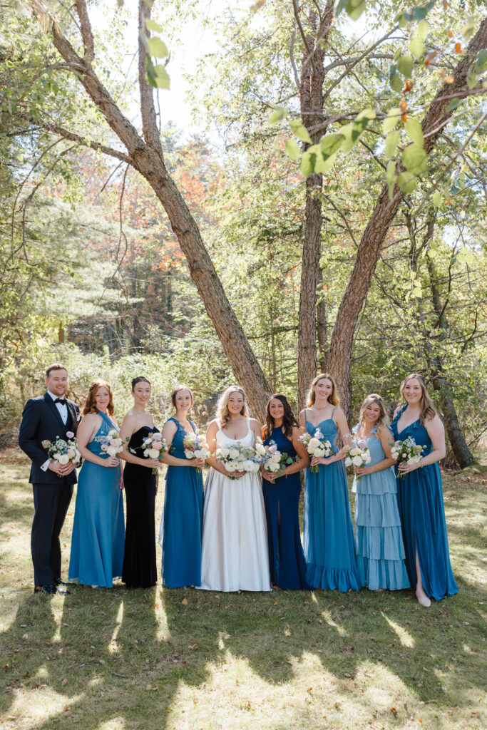 • Bride surrounded by her bridesmaids holding lush floral bouquets in Maine