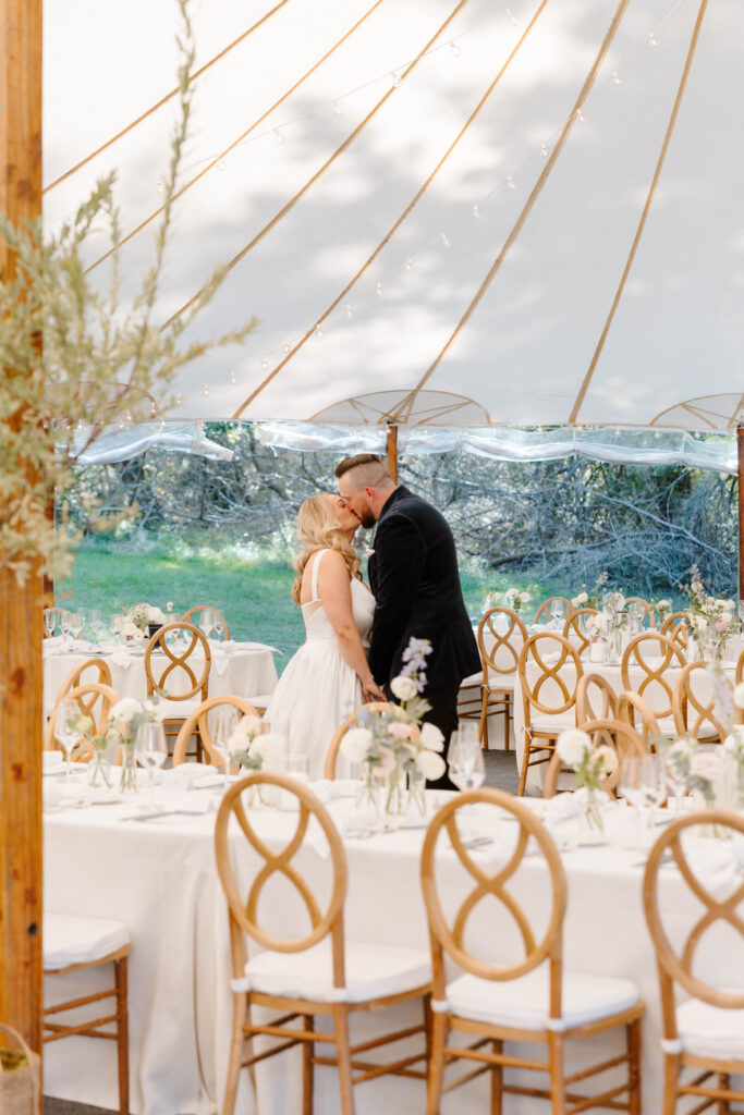 Bride and groom portraits under the reception tent surrounded by candles and elegant floral décor on Great Diamond Island