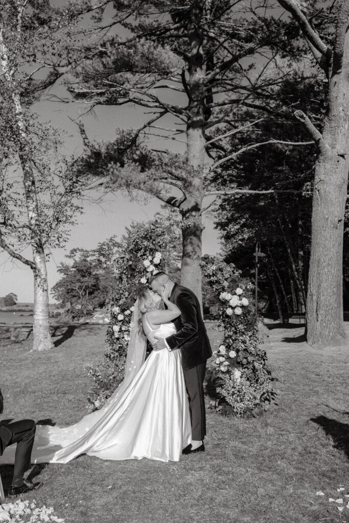 Bride and groom exchanging vows under the trees during their Maine island wedding