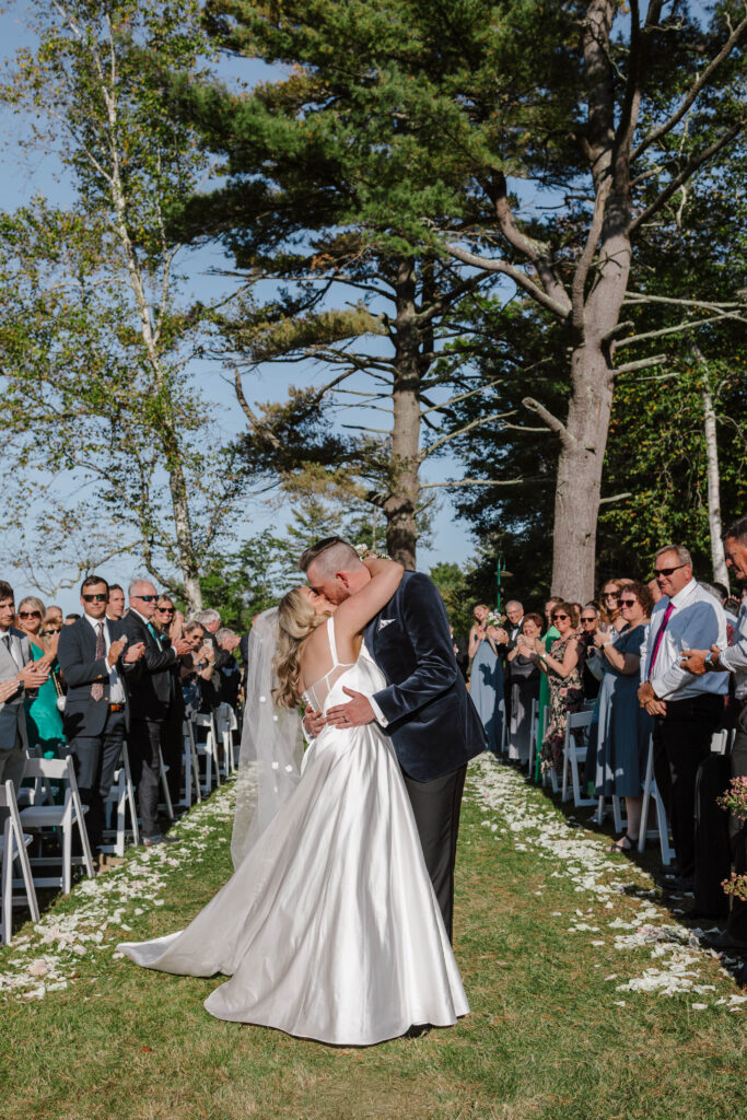 Bride and groom exchanging vows under the trees during their Maine island wedding