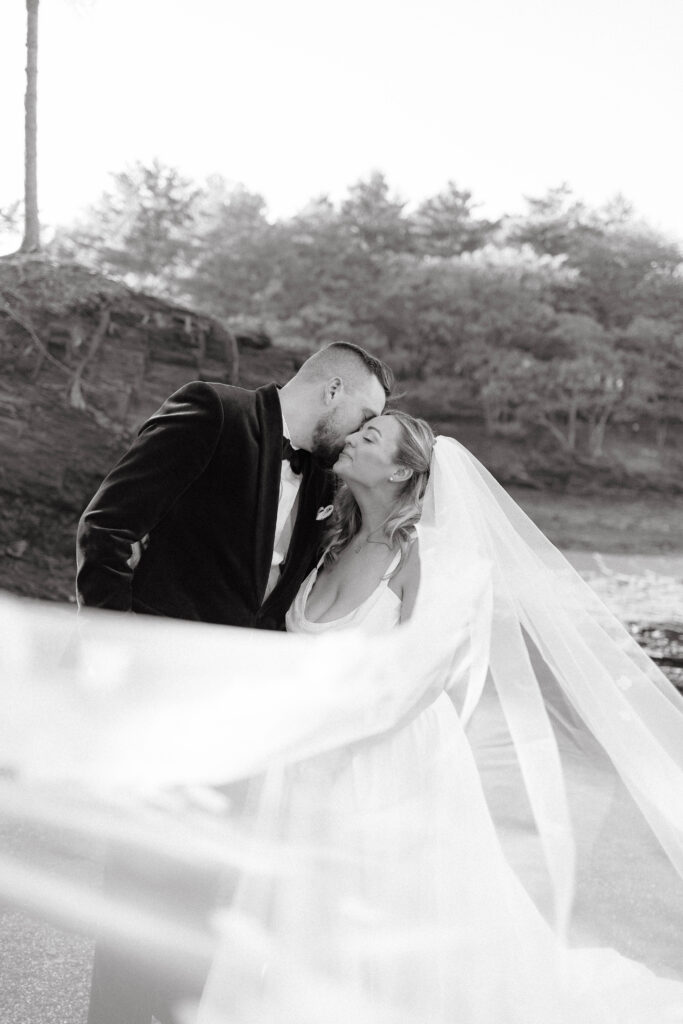 Bride and groom walking hand in hand along the shoreline during their coastal Maine wedding