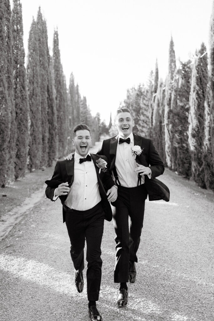 Grooms run towards camera having fun in Tuscany