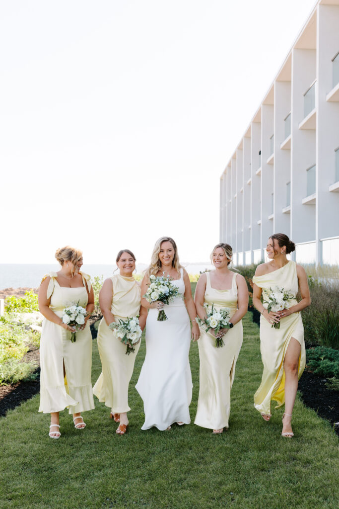 Bridesmaids walk with bride down grass path at Cliff House in Maine.