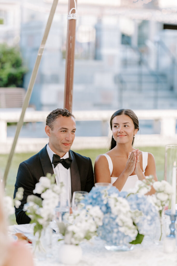 bride and groom watch speeches being given at reception