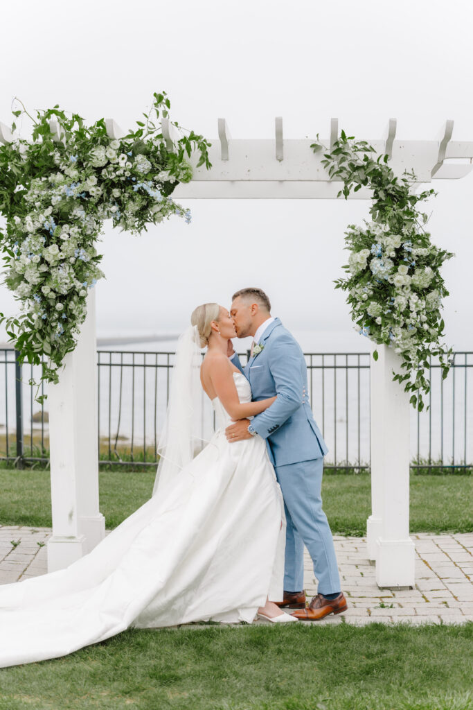 bride and groom exchange first kiss at wedding ceremony taken by coastal wedding photographer in maine