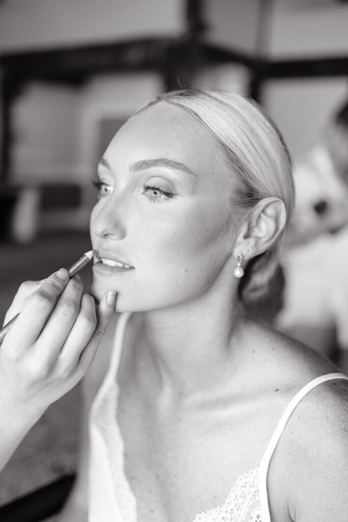 Bride getting makeup done on wedding day.