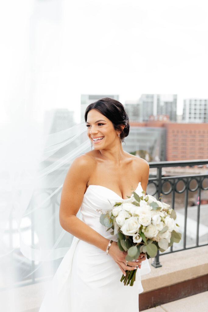 bride smiles with vail flying in the wind in boston, massachusetts