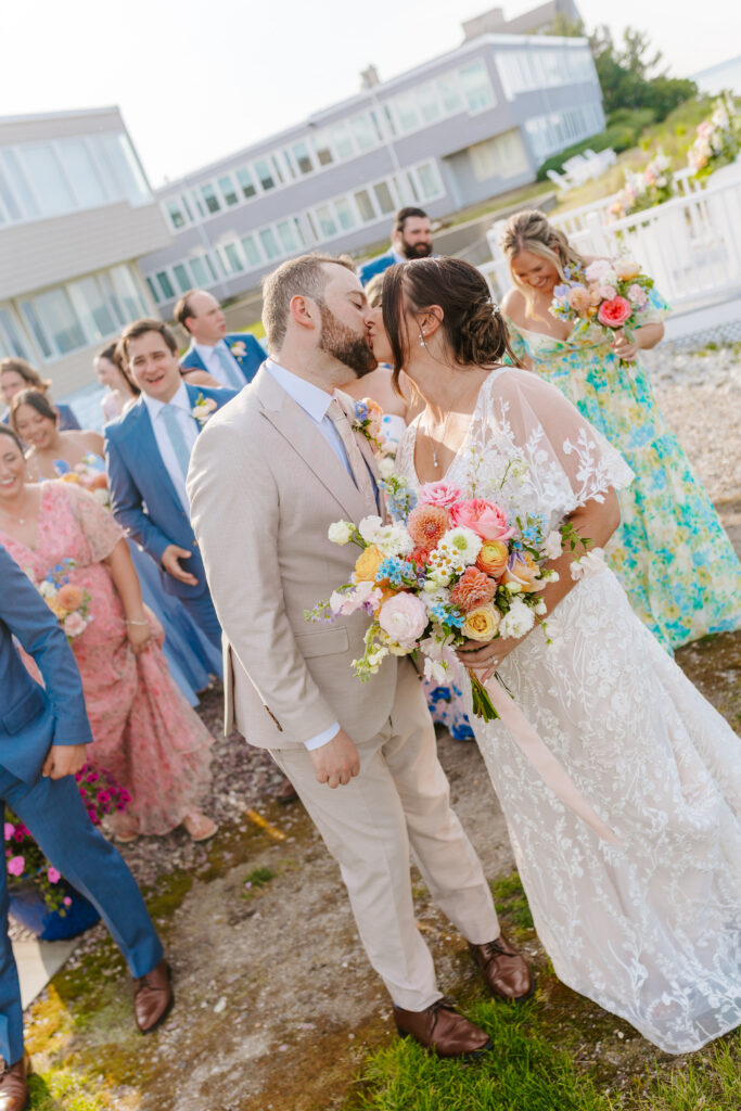bride and groom share kiss with wedding party