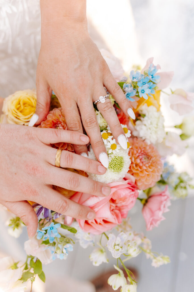 detail shots of bride and groom wedding rings while they hold hands