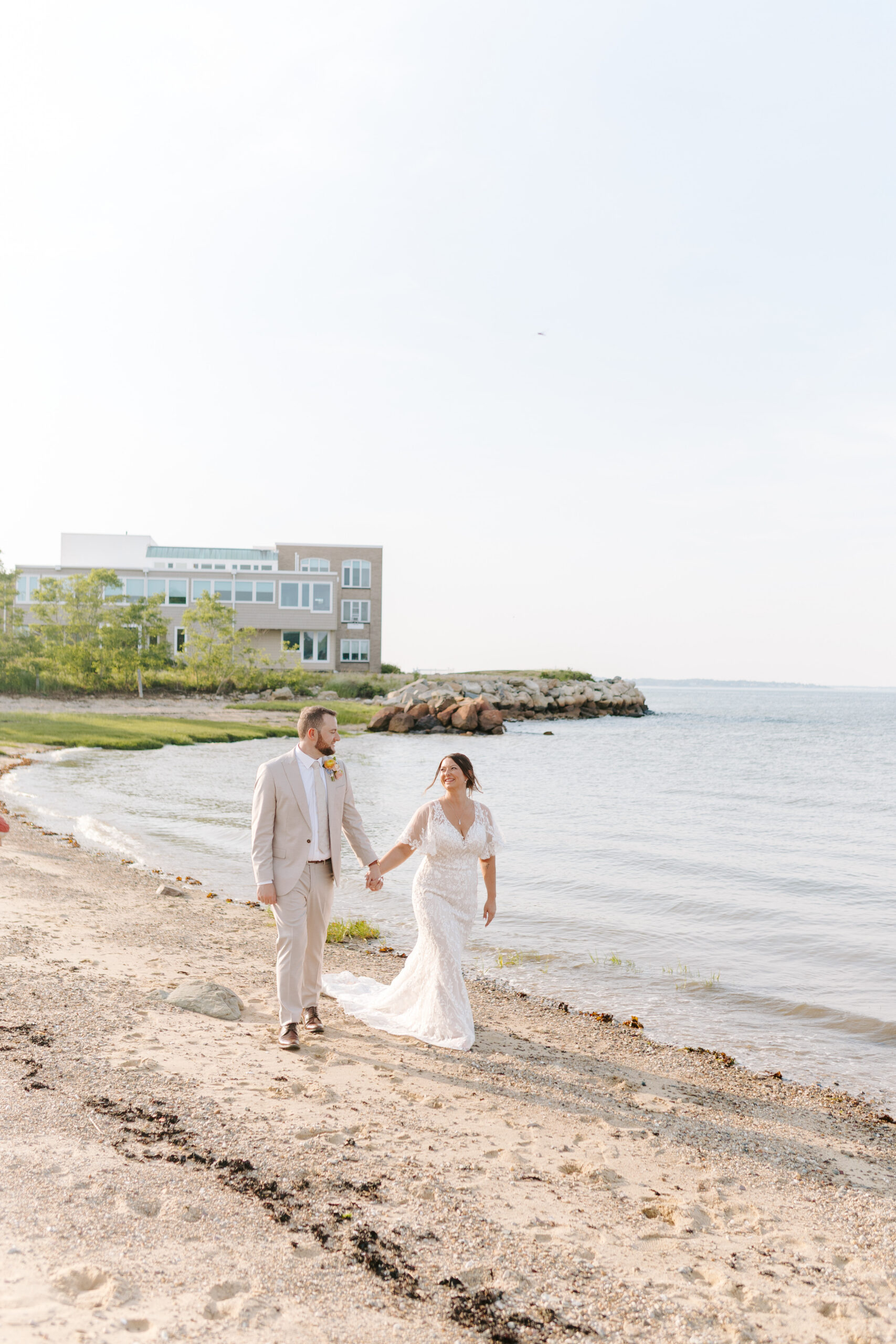 bride and groom hold hands and walk on beach taken by cape cod wedding photographer
