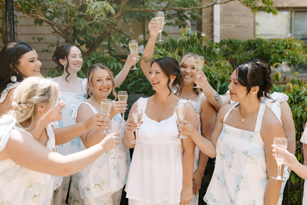 bride and bridesmaids cheer with champagne getting ready on wedding day