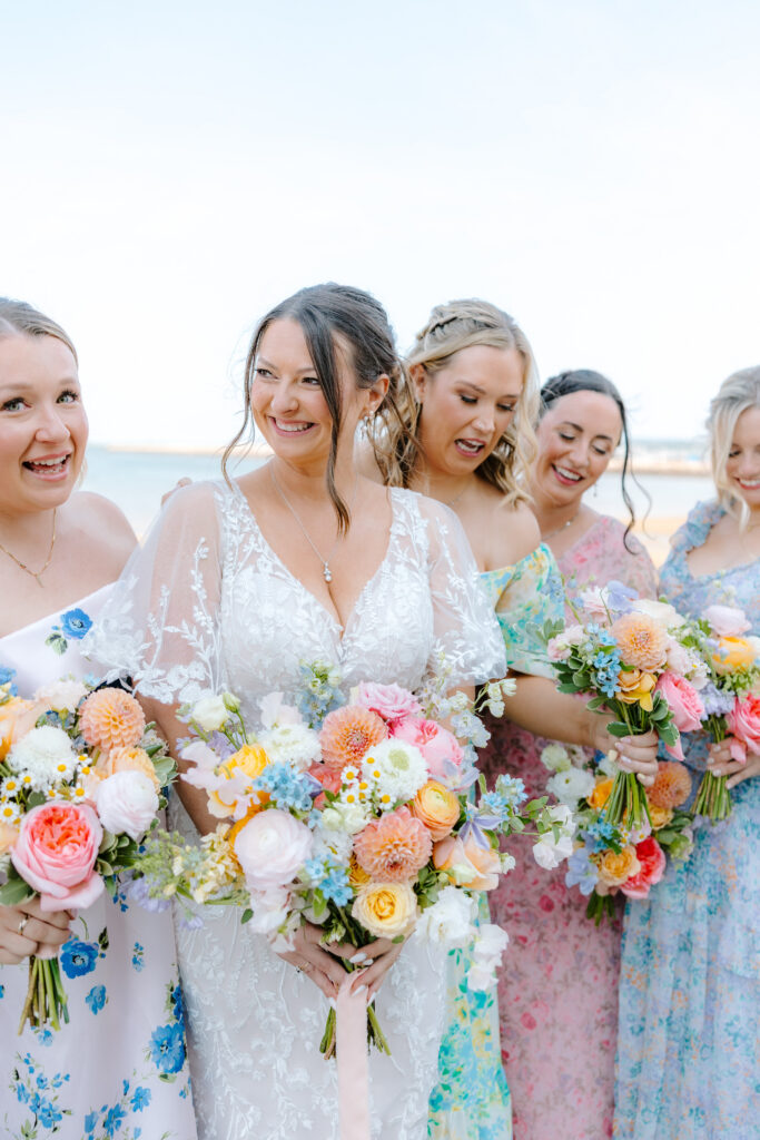 bride smiles with bridesmaids holding bouquets