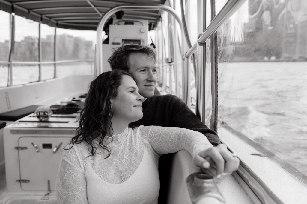 Black and white candid engagement photo on Boston harbor water taxi