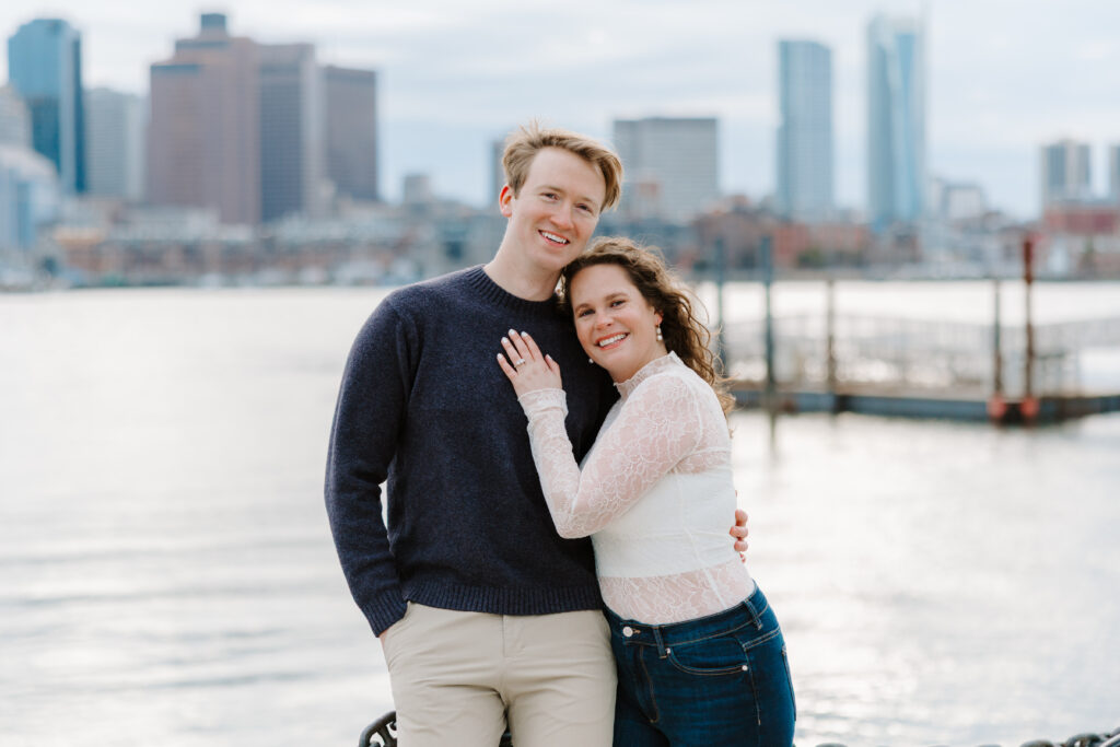 Romantic Boston engagement portrait with skyline view and waterfront railing