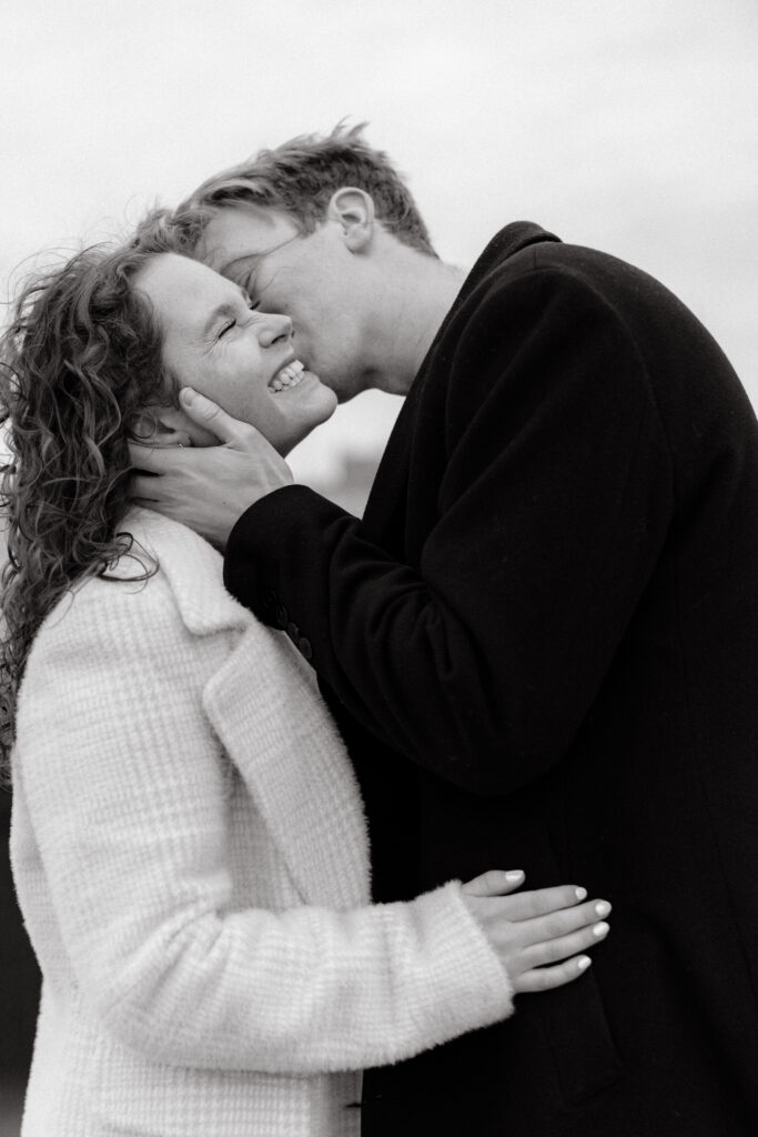 Close up black and white engagement photo of couple laughing and kissing in Boston