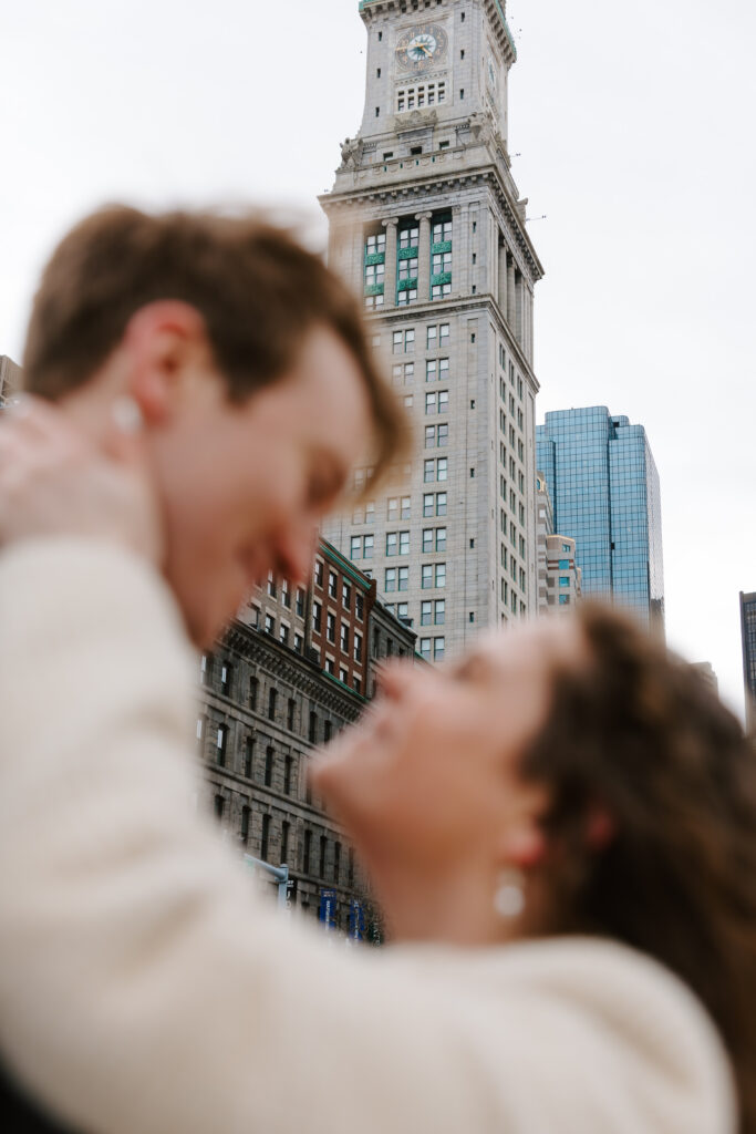 Romantic Boston engagement photo with city skyline and intimate foreground blur