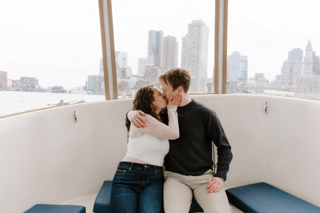 Couple kissing on water taxi with Boston skyline in the background engagement session
