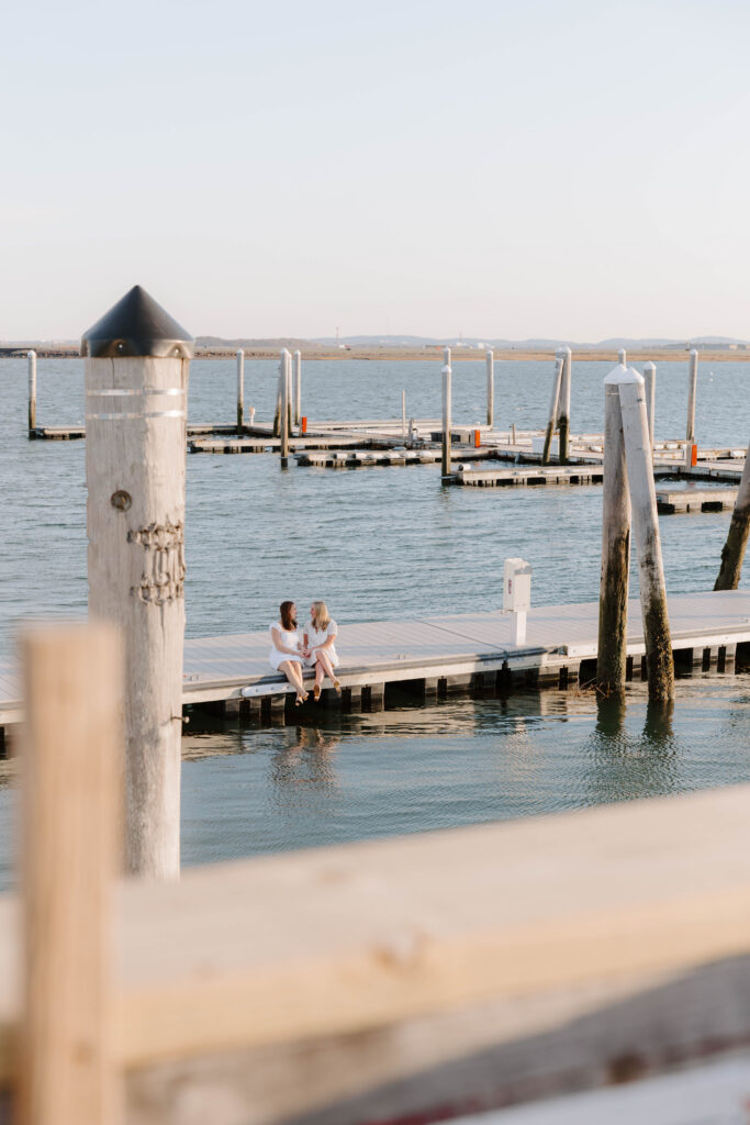 Wide shot of couple sitting on dock surrounded by water in East Boston