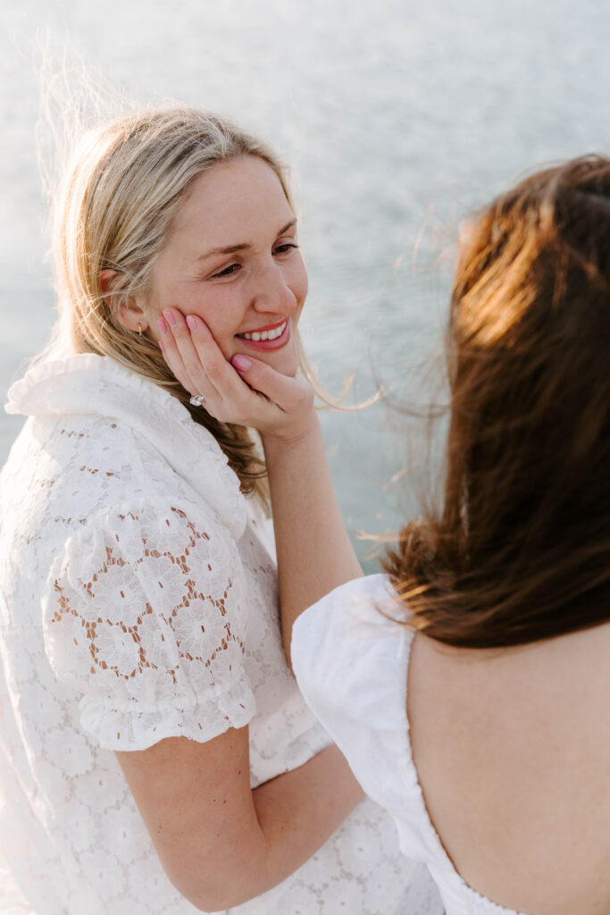 Close up of woman smiling while partner touches her face during engagement session