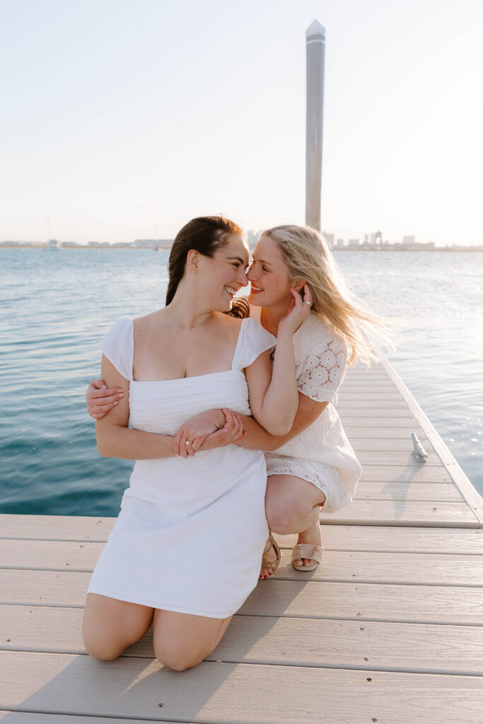 Couple sitting on a dock in East Boston with water and marina in background