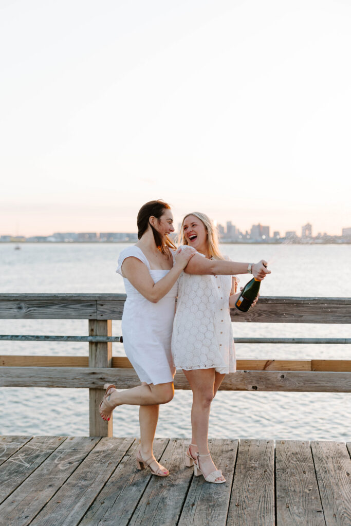 Playful champagne celebration photo on Boston pier at golden hour