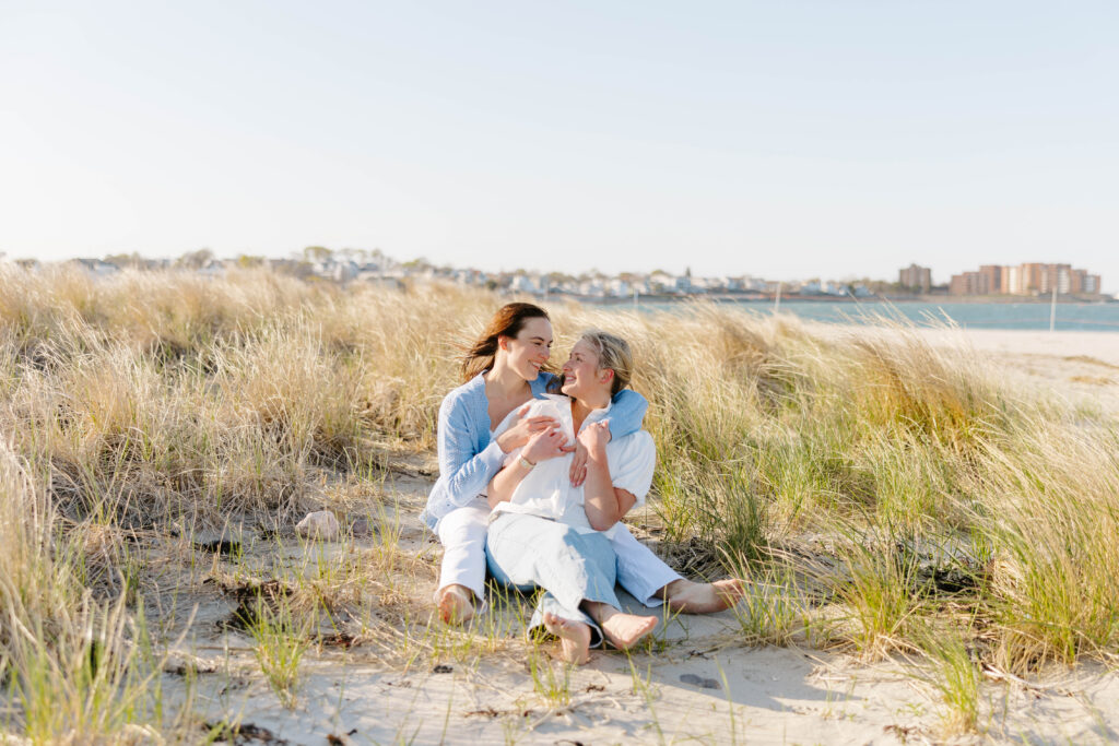 Couple sitting together in grass dunes near East Boston waterfront
