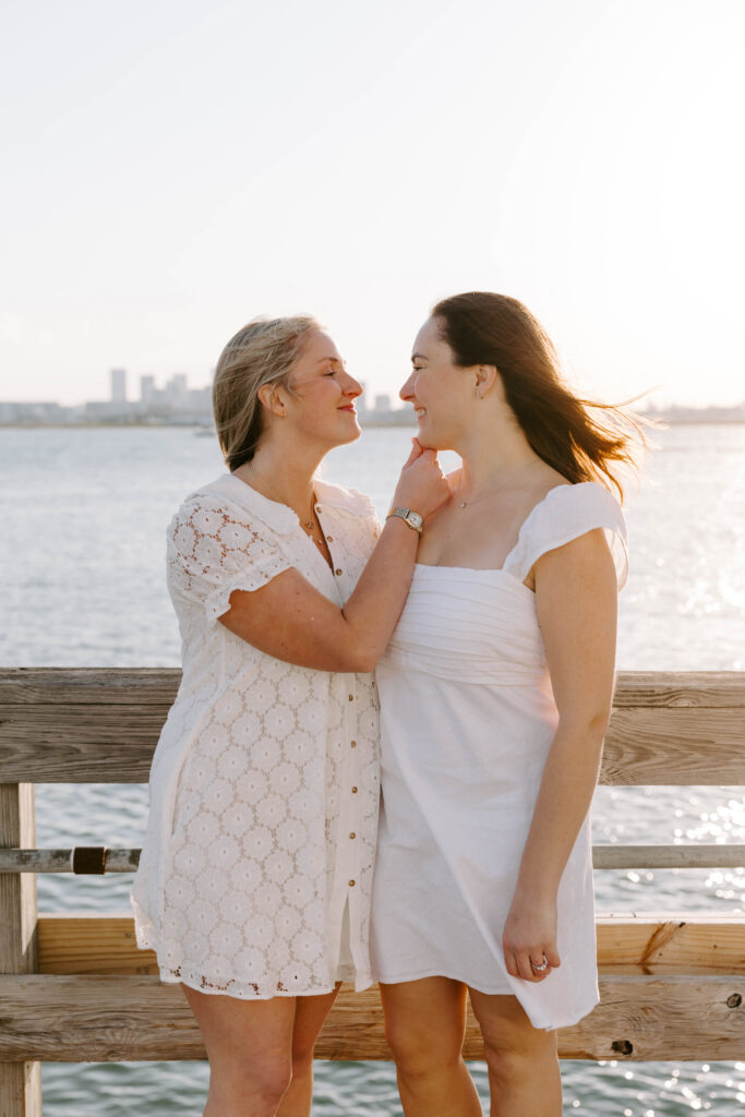 Couple embracing on dock with Boston skyline in background