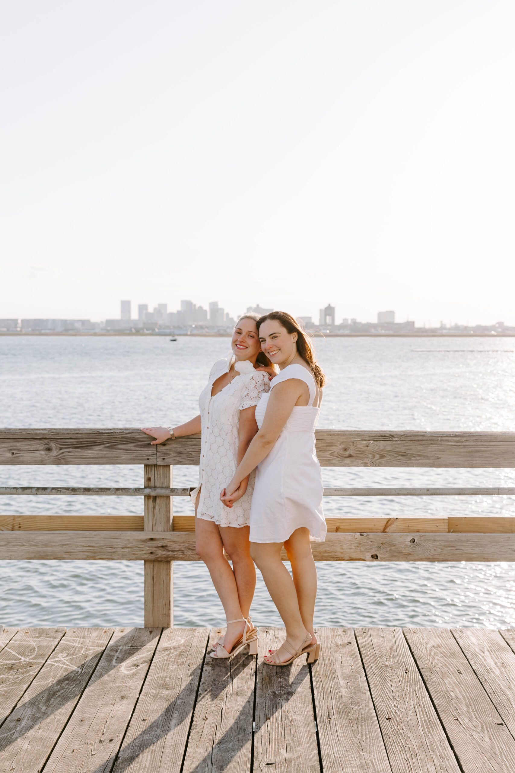 Couple standing on pier with Boston skyline in background