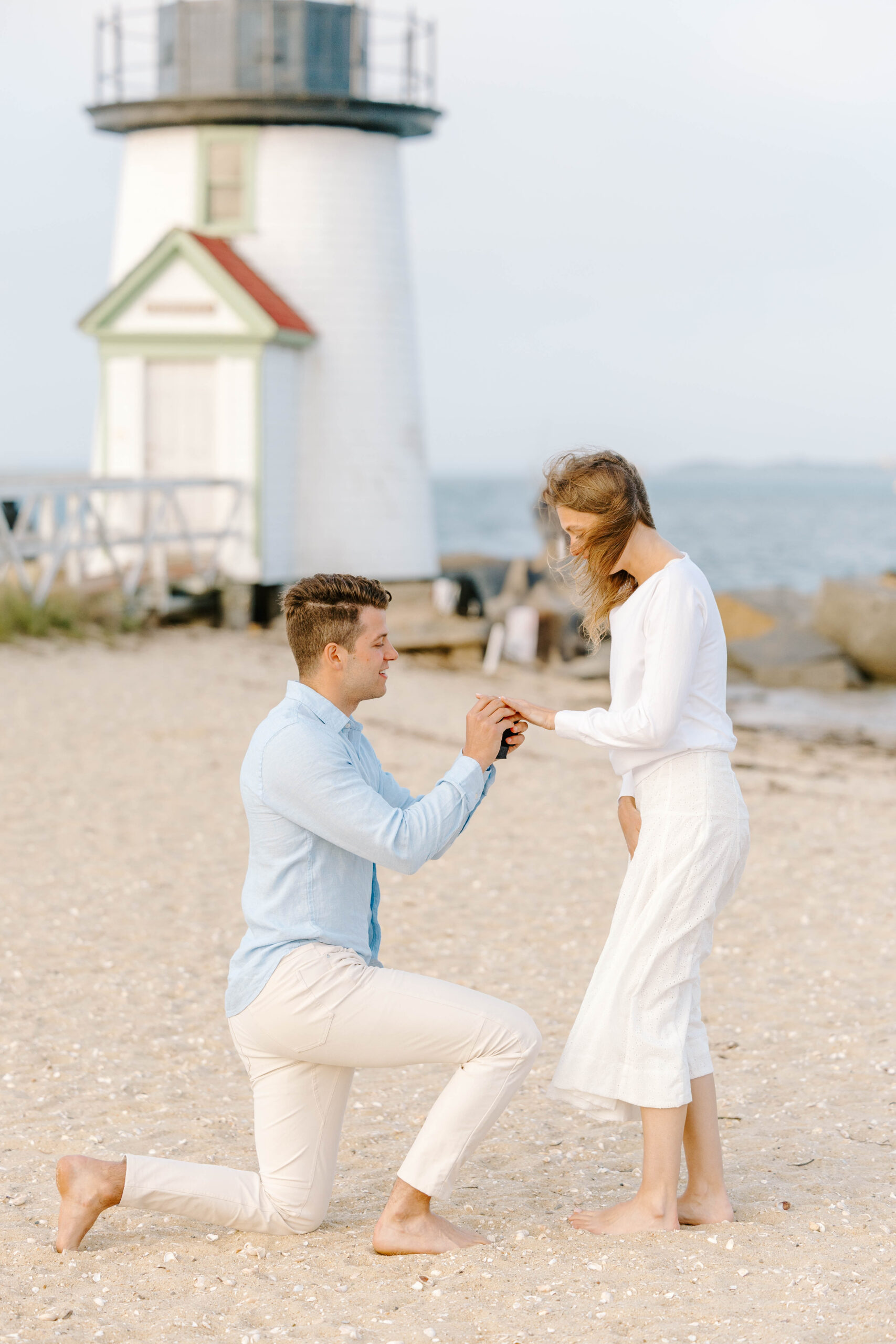 man puts engagement ring on woman on beach taken by wedding photographer