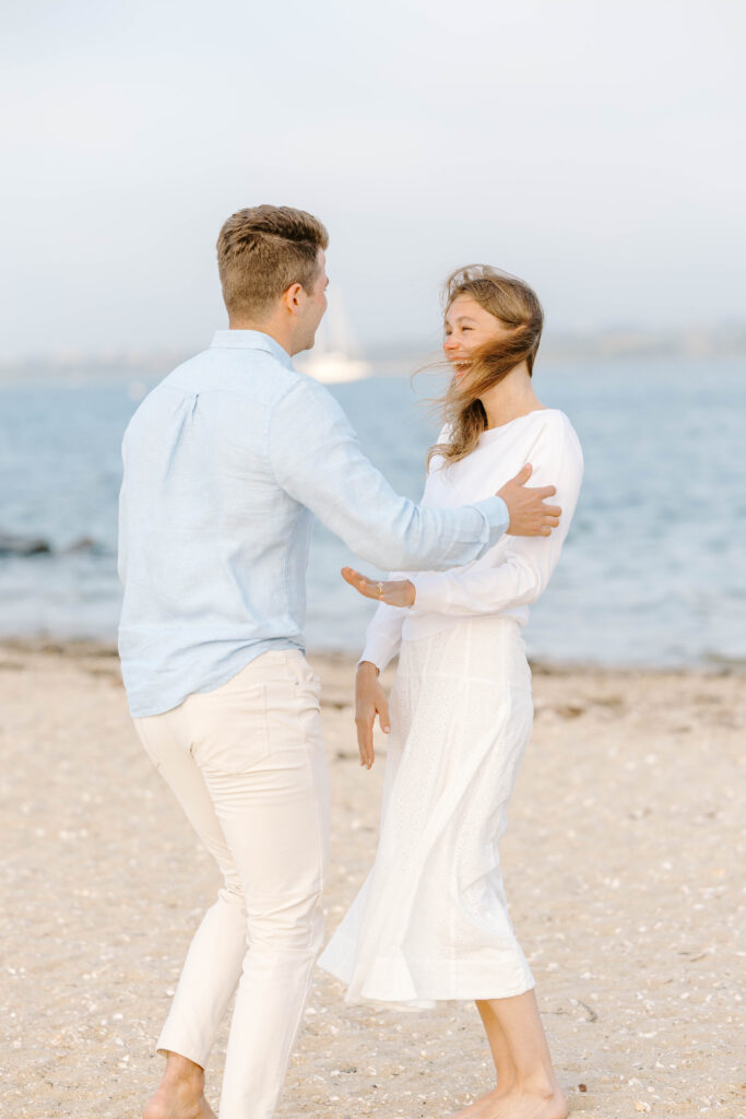 man and woman celebrate engagement on beach in massachusetts