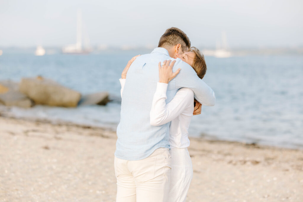 woman and man hug after proposal on beach