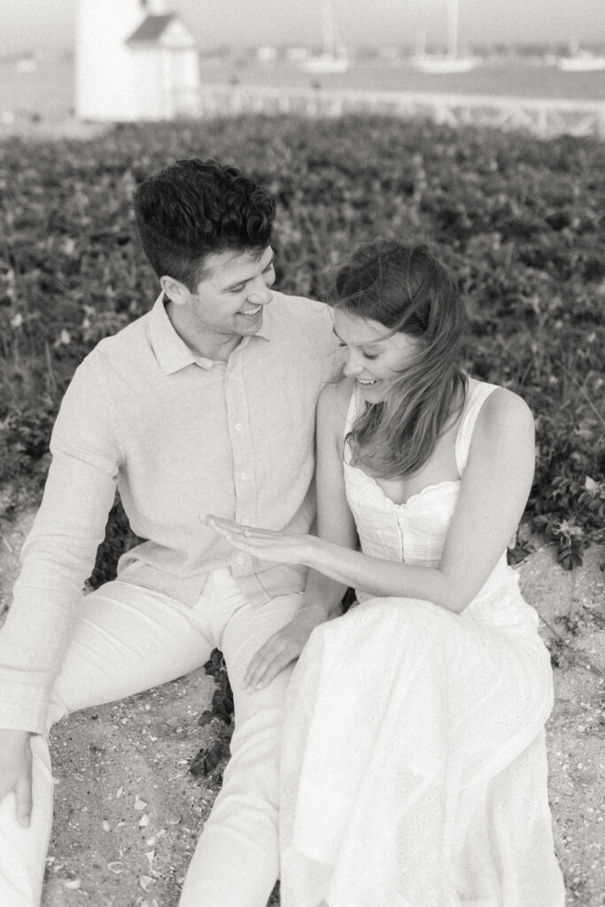 black and white photo of woman looking at engagement ring and smiling