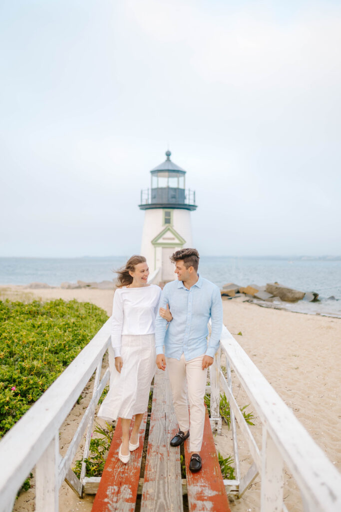couple walks on bridge at brant point lighthouse in nantucket