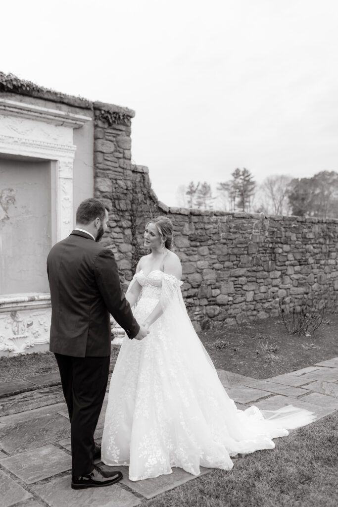 black and white photo of bride and groom holding hands on wedding day in rhode island