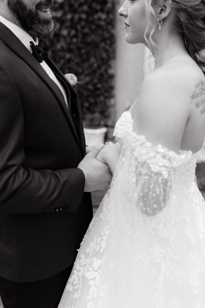 close up black and white photo of bride and groom holding hands on wedding day in rhode island