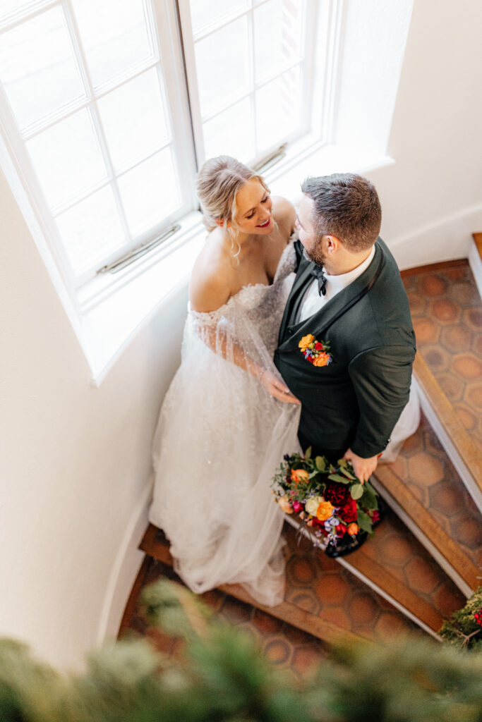 bride and groom smile at each other on stair case at Shepherd’s Run