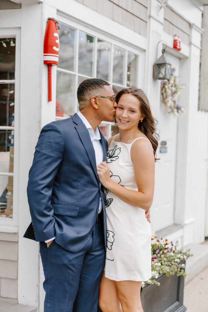 Couple embracing outside coastal storefront in downtown Rockport Massachusetts