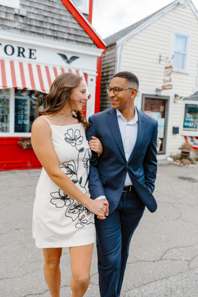 Couple walking and smiling in downtown Rockport Massachusetts engagement session