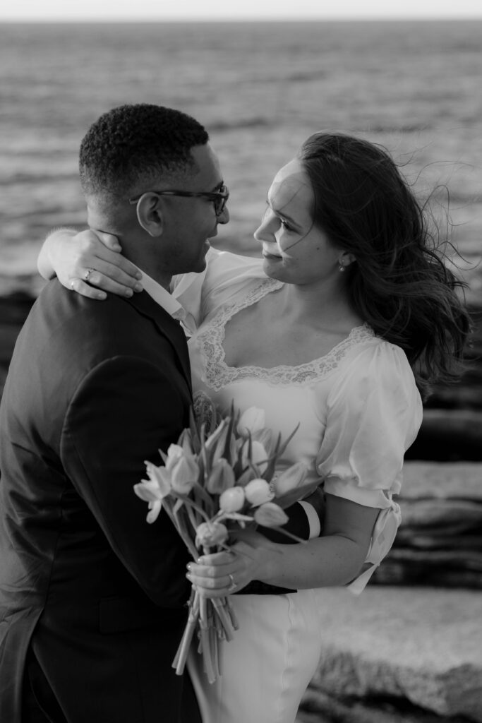 Black and white coastal engagement portrait with ocean in background