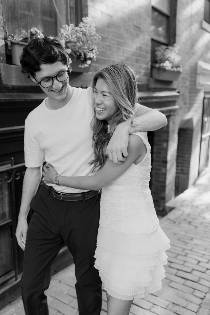 Man and woman laugh together walking on cobblestone in Boston, Massachusetts.