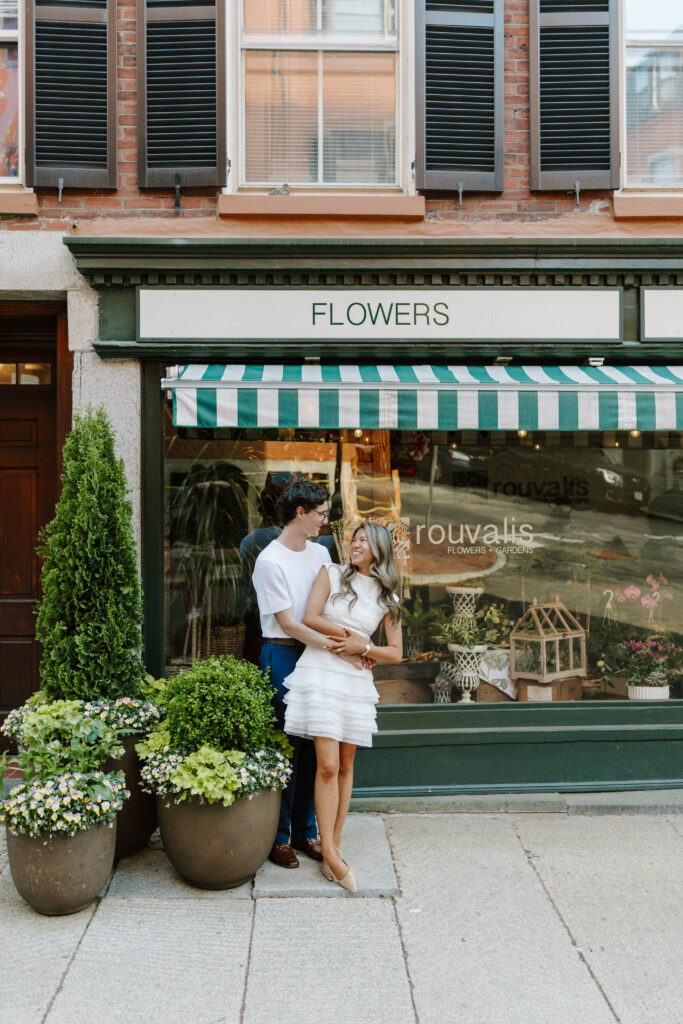 Couple embracing outside a flower shop during engagement photos in Beacon Hill Boston