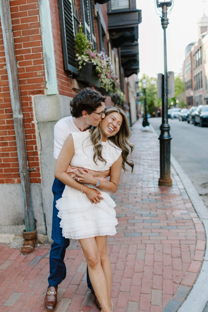 Couple laughing together on a cobblestone sidewalk in Beacon Hill Boston