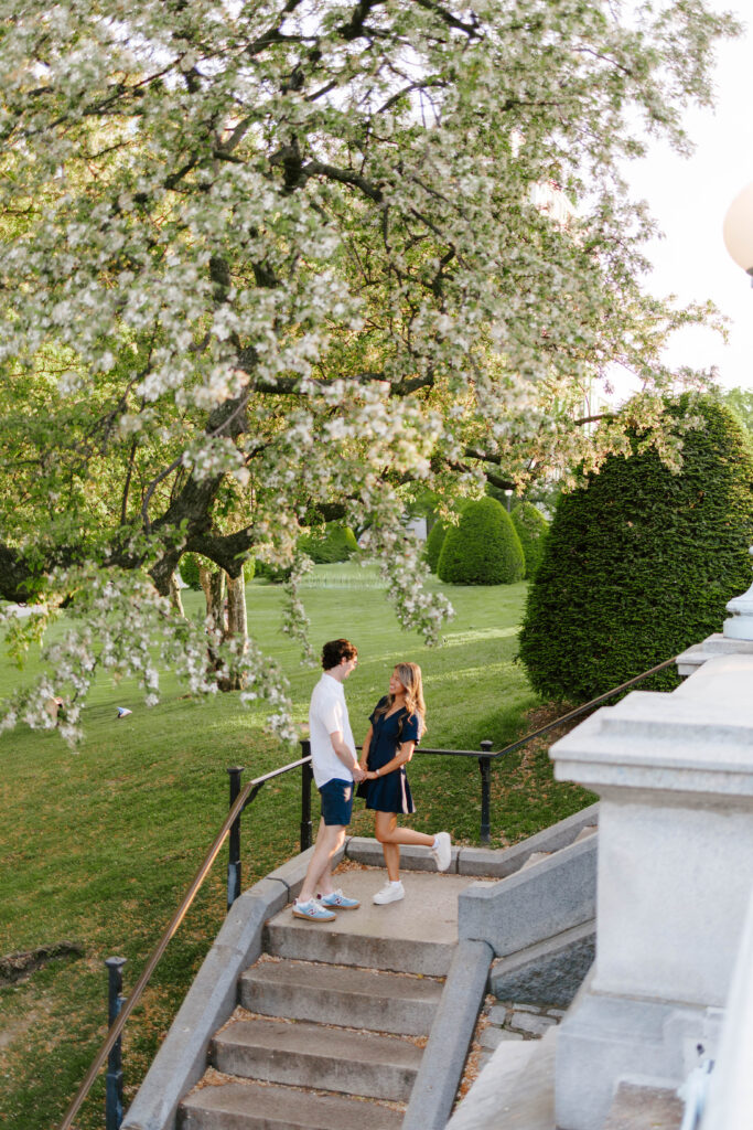 Candid engagement photo of couple walking together through Boston Common park