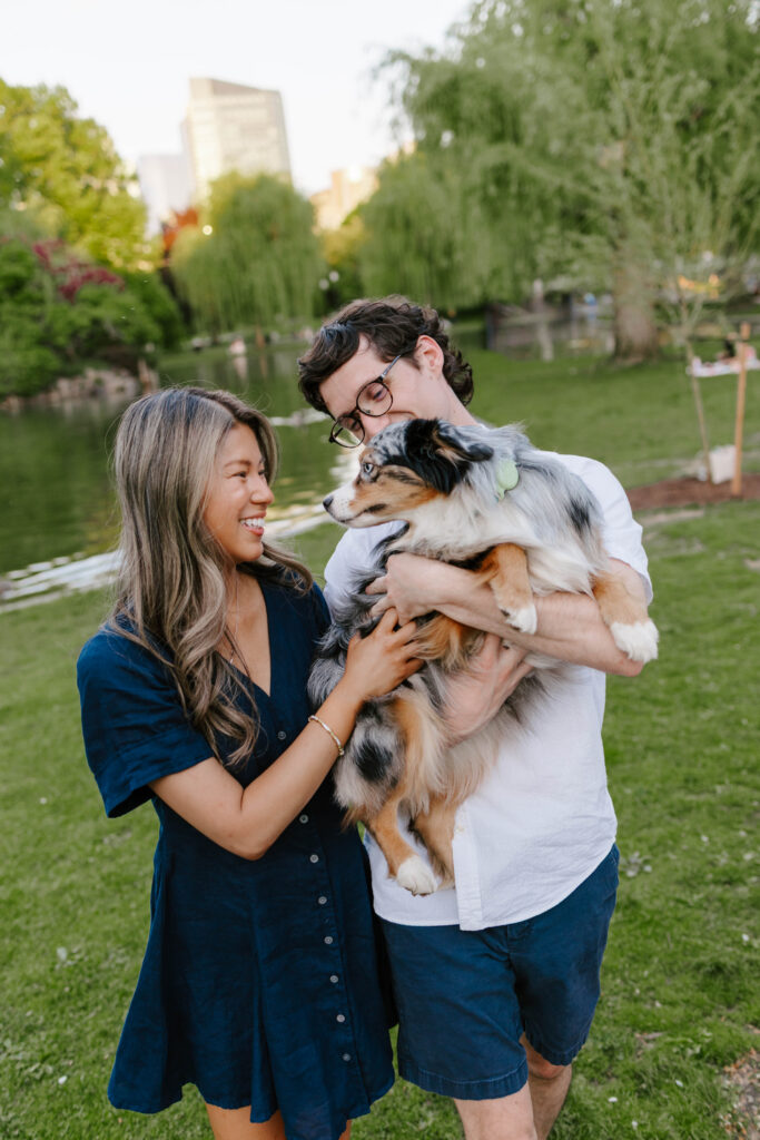 Couple holding their dog during engagement photos in Boston Common