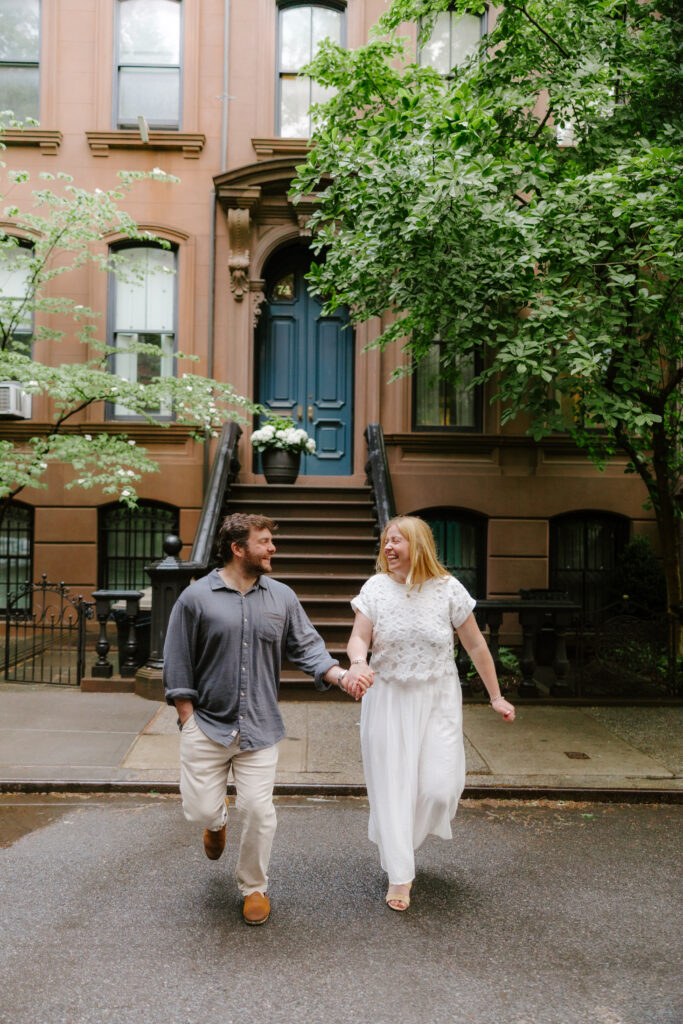 Couple walking the streets of NYC with brown stones in the background. Photo taken by New York City photographer