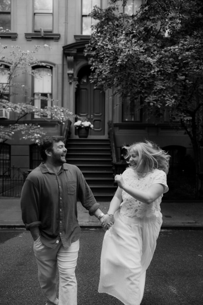 Black and white candid engagement photos outside Manhattan brownstone in the rain. Photo by Clay Taylor Photo