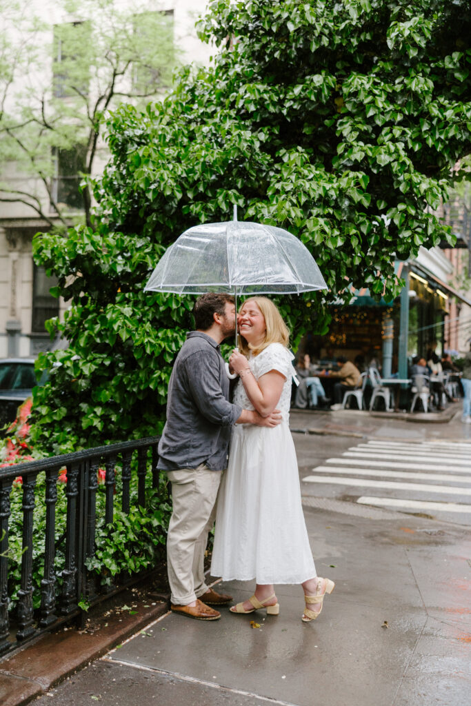 Romantic rainy day engagement portraits in the West Village of New York City with clear umbrella. Photo by Clay Taylor Photo